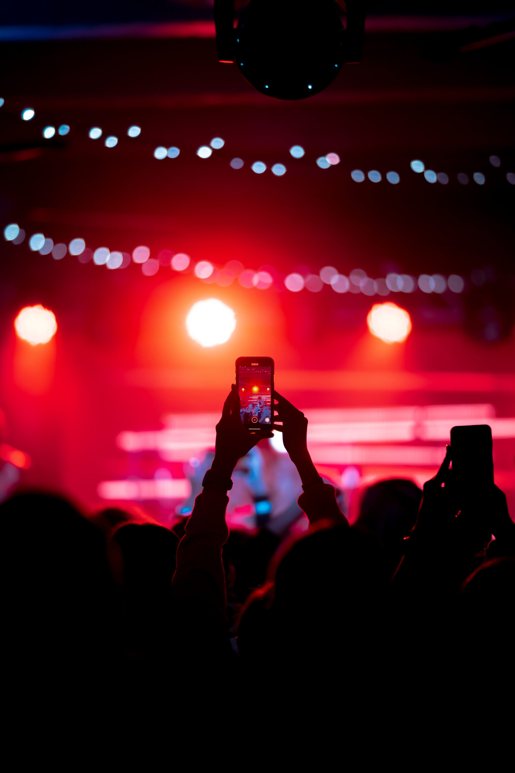 Person close up of recording video with smartphone during a concert.